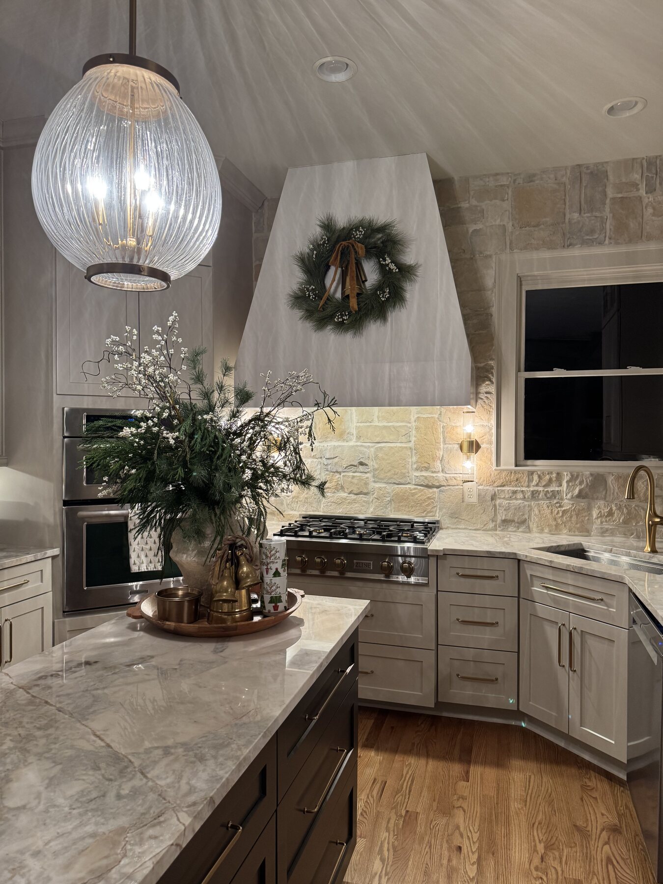 Warm stone kitchen with custom cabinetry and a sculptural pendant